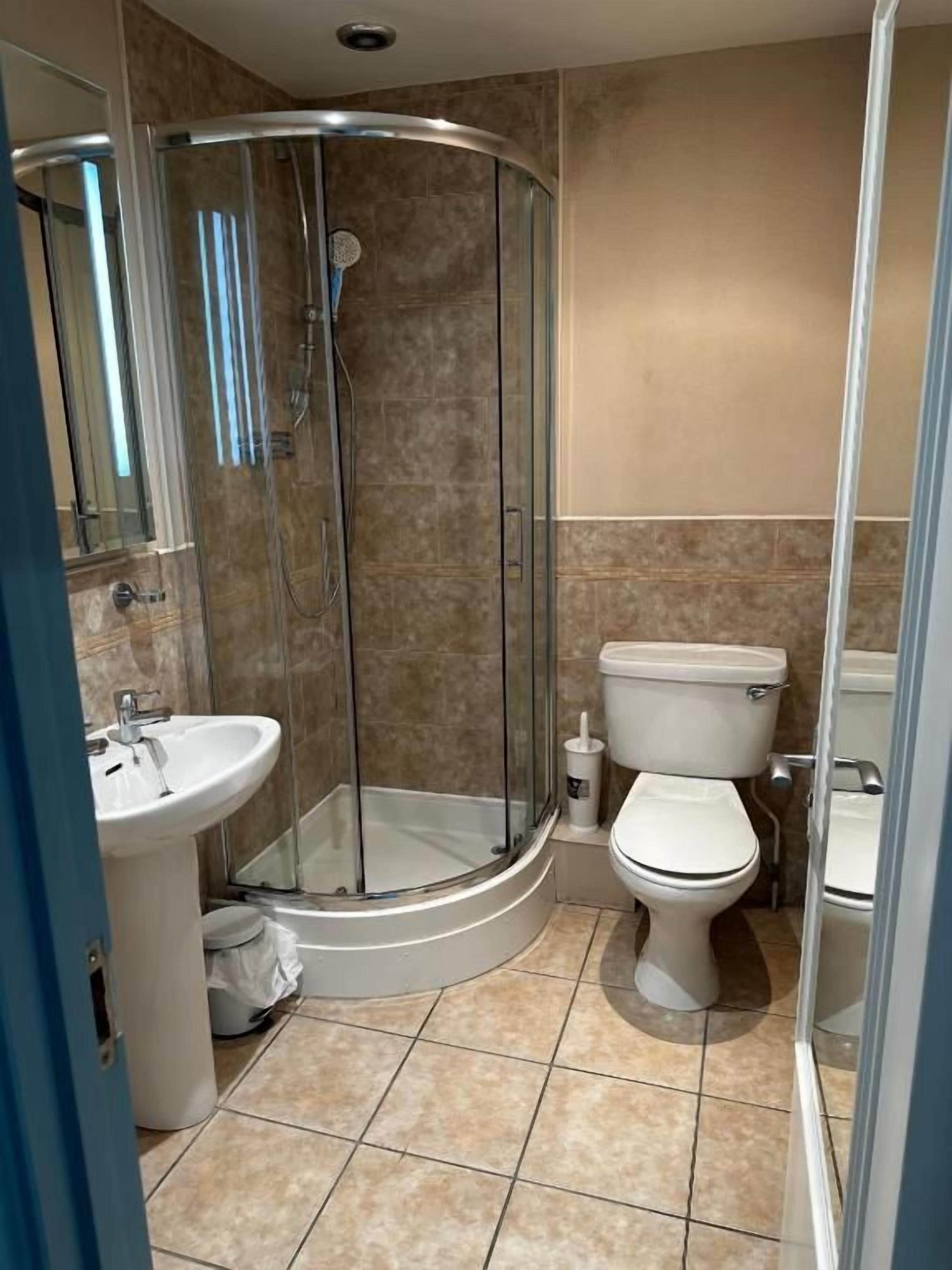 A bathroom with a glass-enclosed shower, a toilet, and a sink.