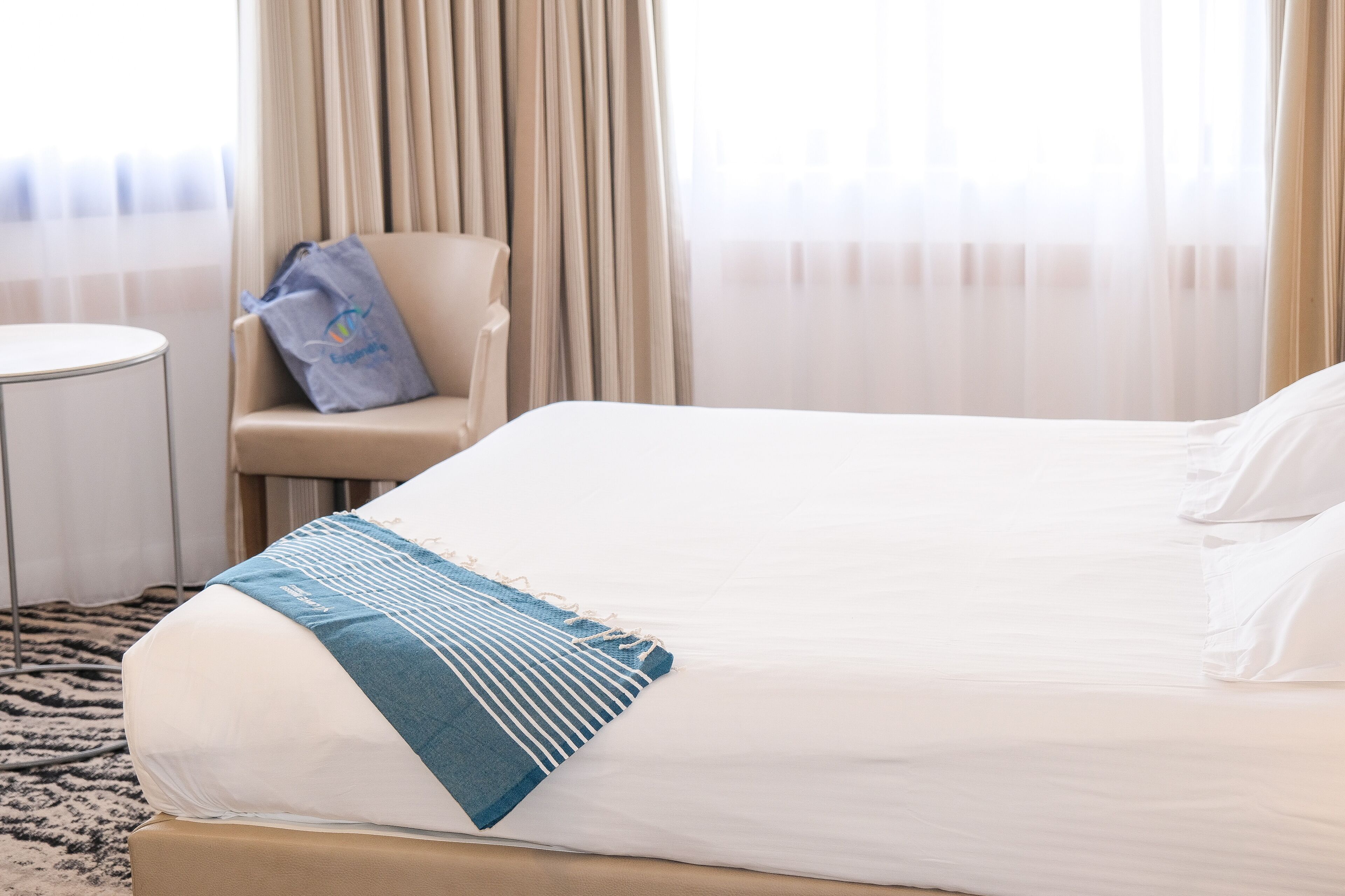 A hotel room with a large bed, a chair, and a small table.