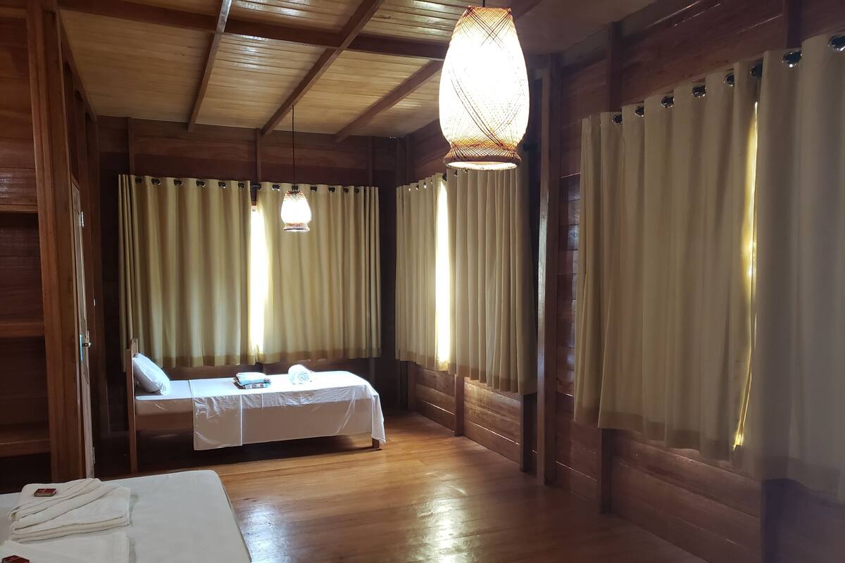 Une pièce en bois avec un lit, une table sur laquelle sont posées des serviettes et un luminaire suspendu.