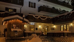 A snow-covered building with a bar and a wooden structure with lights. - Alle Due Spade (Folgaria)