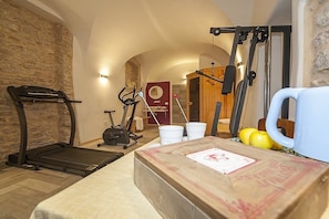 Ein Heimfitnessraum mit Laufband, Crosstrainer und einer Gewichtshalterung.