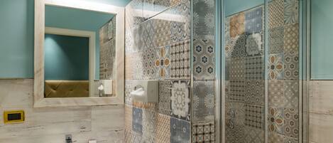 A bathroom with a sink, mirror, and shower with patterned tiles.