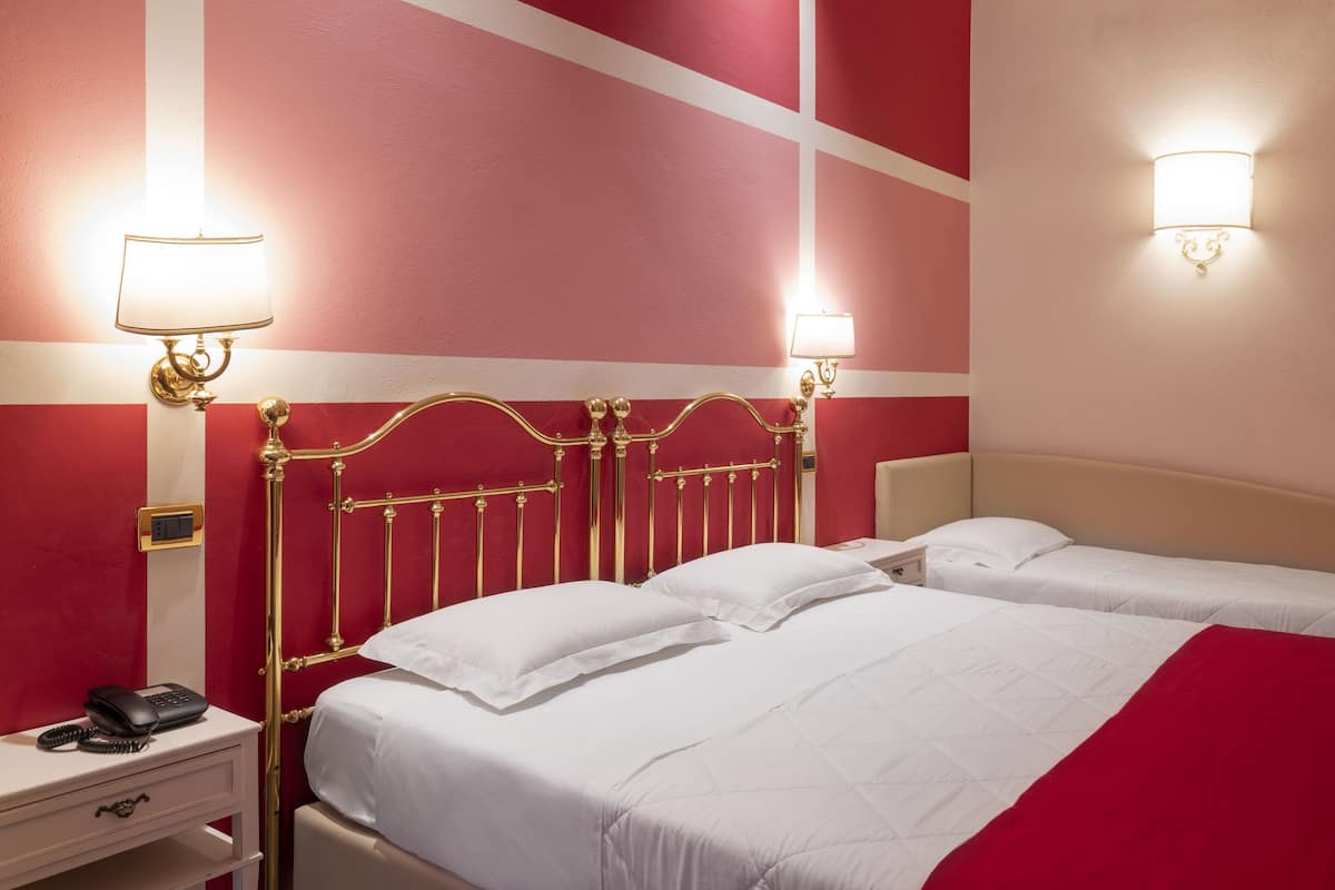 Une chambre d’hôtel avec un lit, des tables de chevet et des lampes fixées au mur.