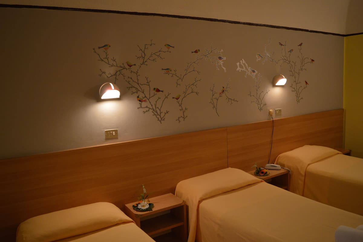 A hotel room with two beds, a wooden headboard, wall-mounted lights, and a decorative wall mural.