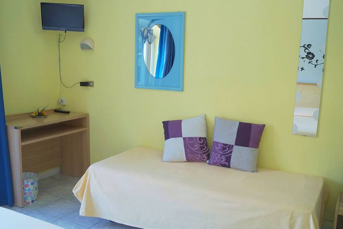 A room with a bed, a desk, a TV, and a wall art piece.