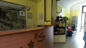 A reception desk with a vintage photo, a sign indicating a camera and film processing service, and a fish tank in the background.