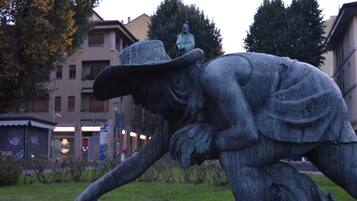Eine Statue eines Mannes mit Hut, der sich über eine Steinmauer beugt.