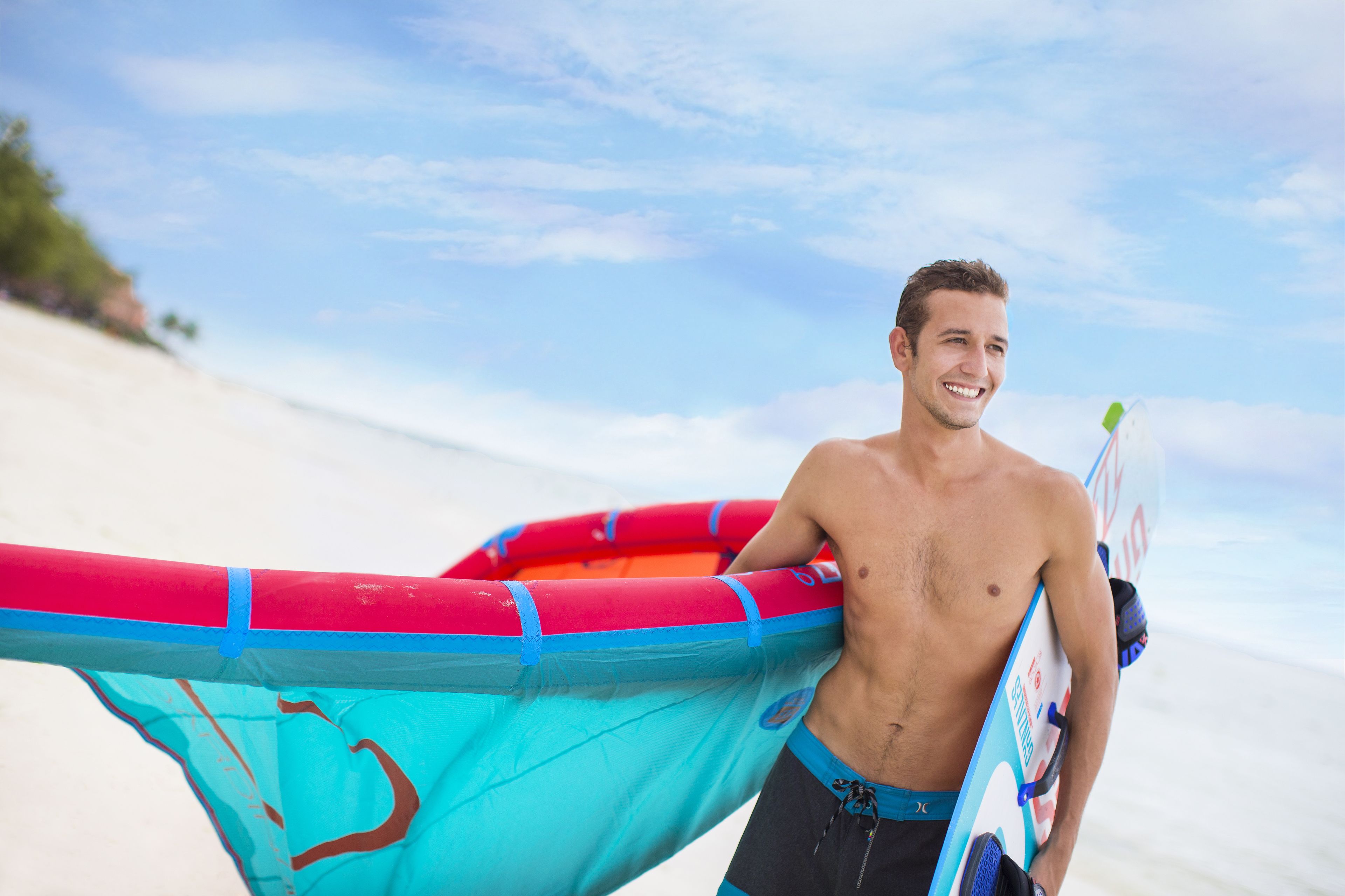 Un homme tenant une planche de surf et un radeau gonflable sur une plage.