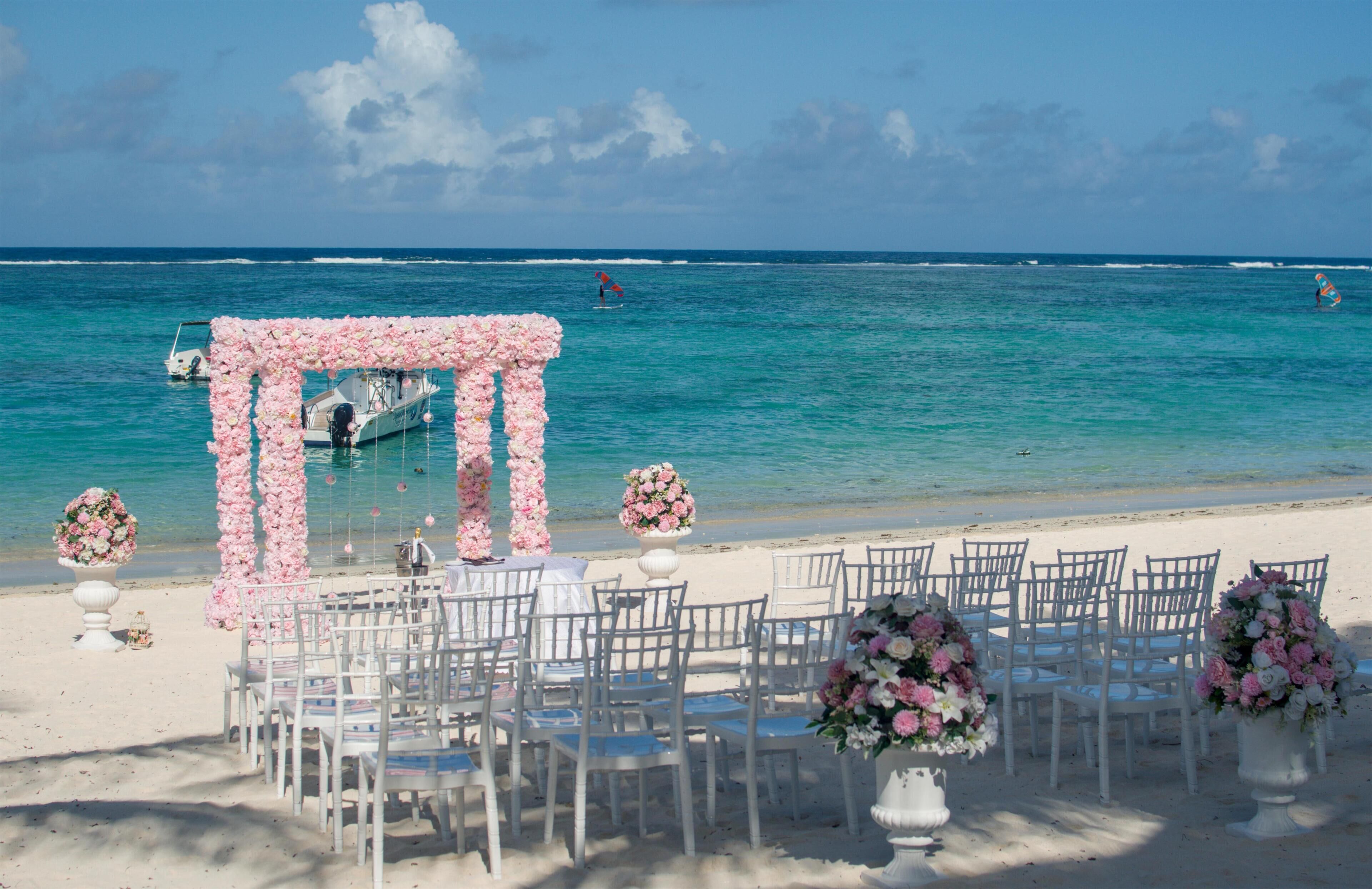 Decoración para una boda en la playa, con sillas y adornos florales.