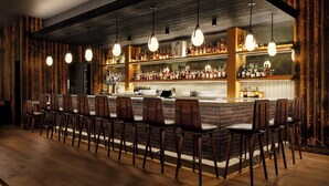 A bar area with wooden accents, a long counter, and multiple hanging light fixtures. - Aloft by Marriott Asheville Downtown (Asheville)