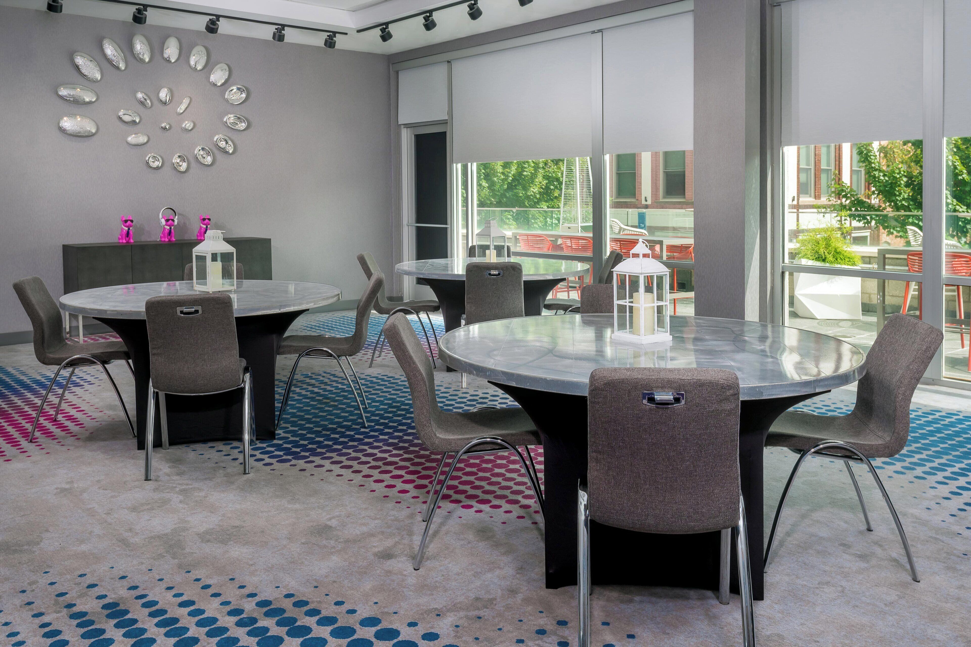 Een moderne vergaderruimte met een glazen tafel, grijze stoelen en een kamerbreed tapijt met dessin.