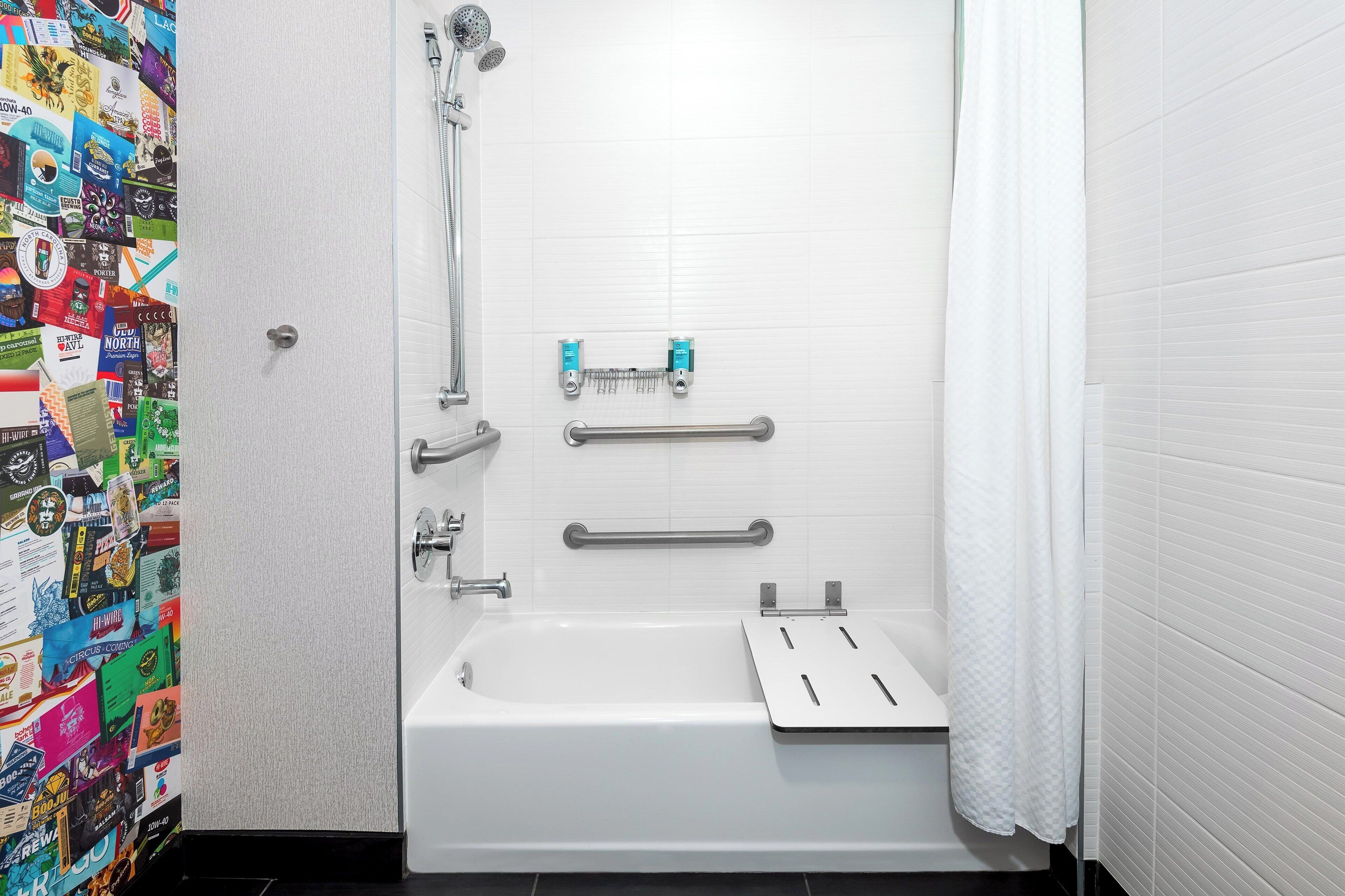 Un baño con bañera blanca, cabezal de ducha, barras de apoyo y un perchero para toallas.