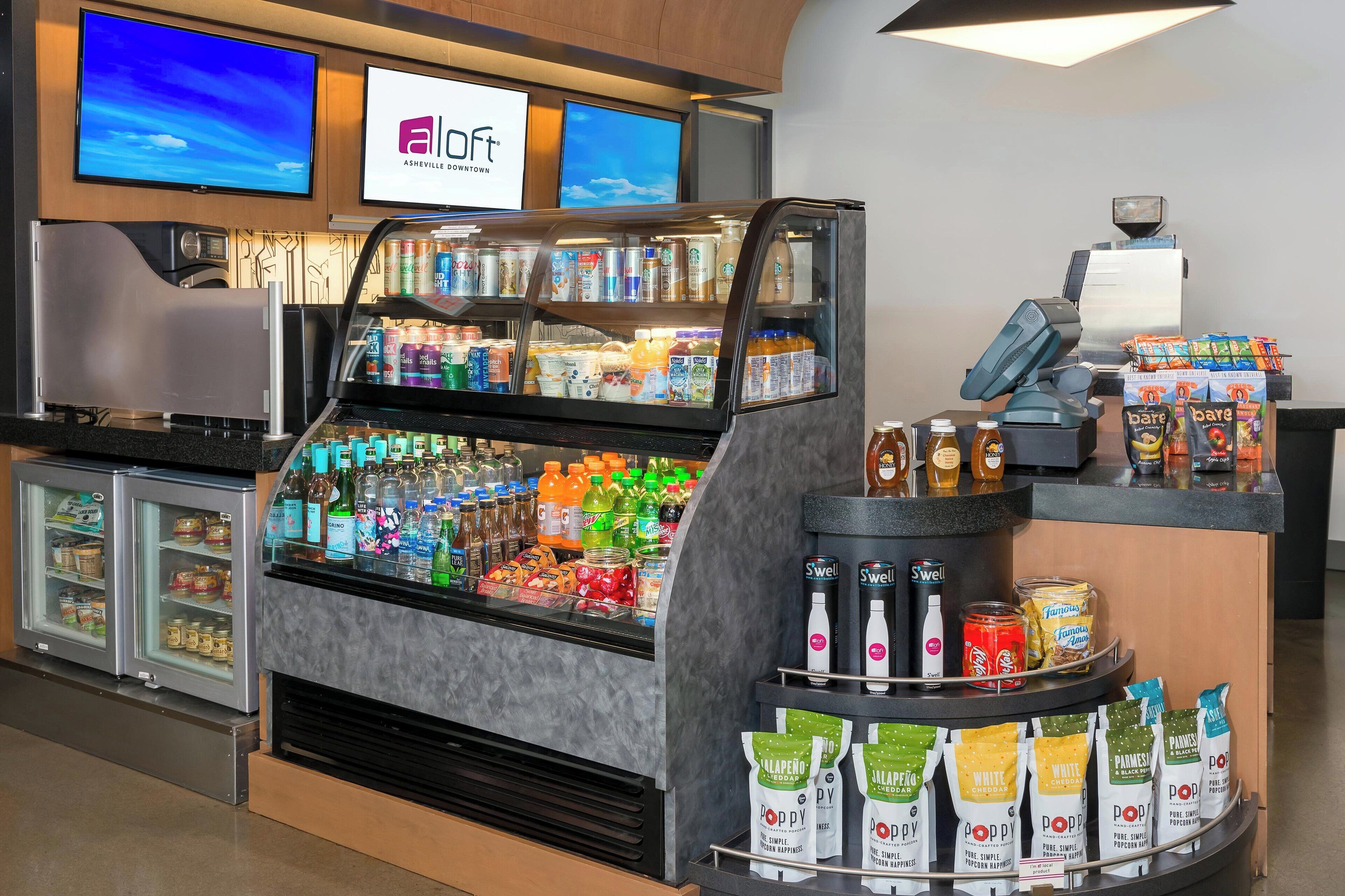 En selvbetjeningsstation med kolde drikkevarer, kaffemaskine og pakker med snacks.