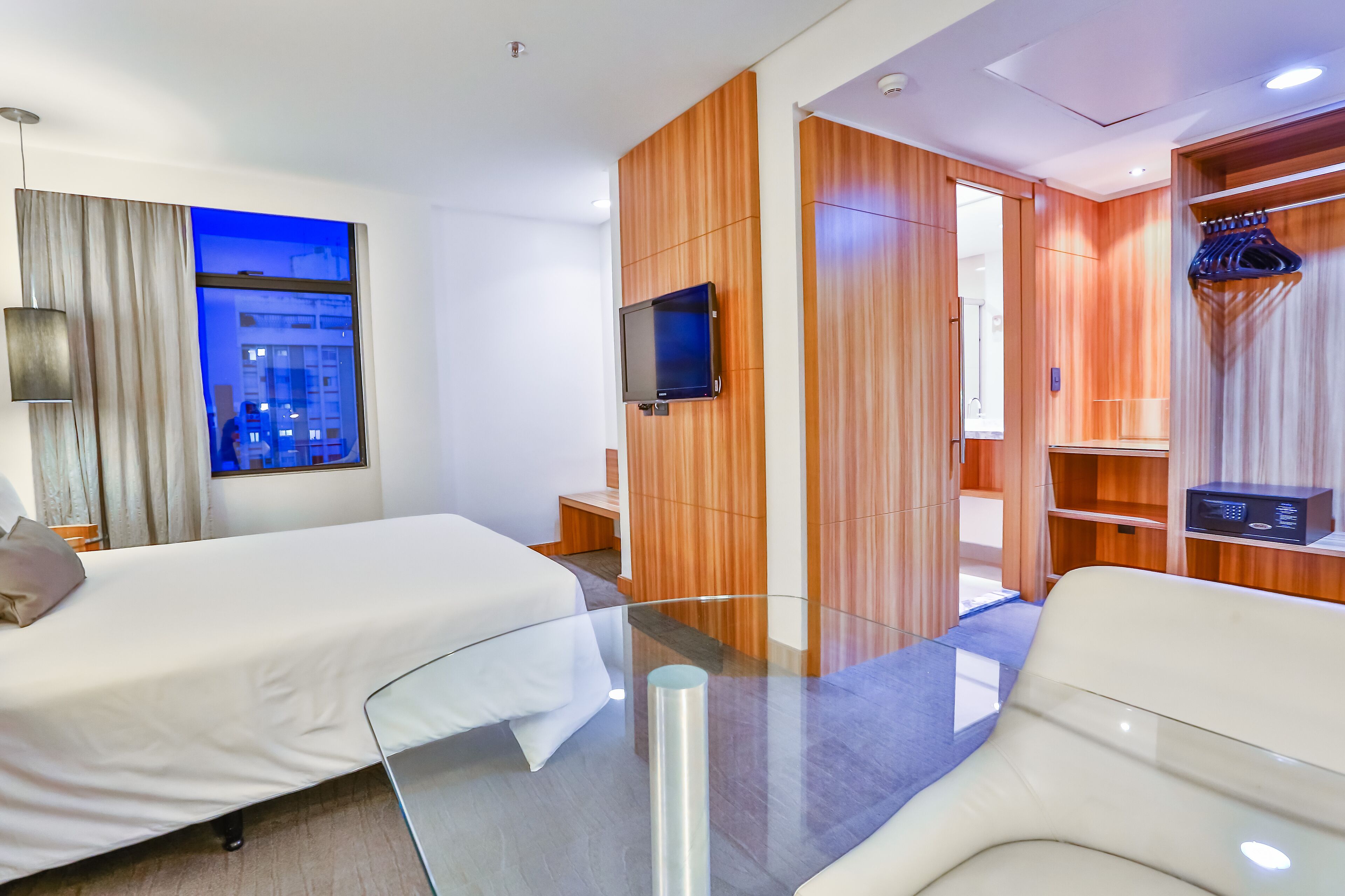 Habitación de hotel con dos camas, televisión, espejo y armario.