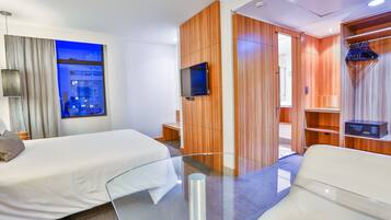 Habitación de hotel con dos camas, televisión, espejo y armario.