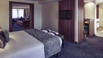 Una habitación de hotel con una cama grande, un televisor montado en la pared y un escritorio con una computadora.
