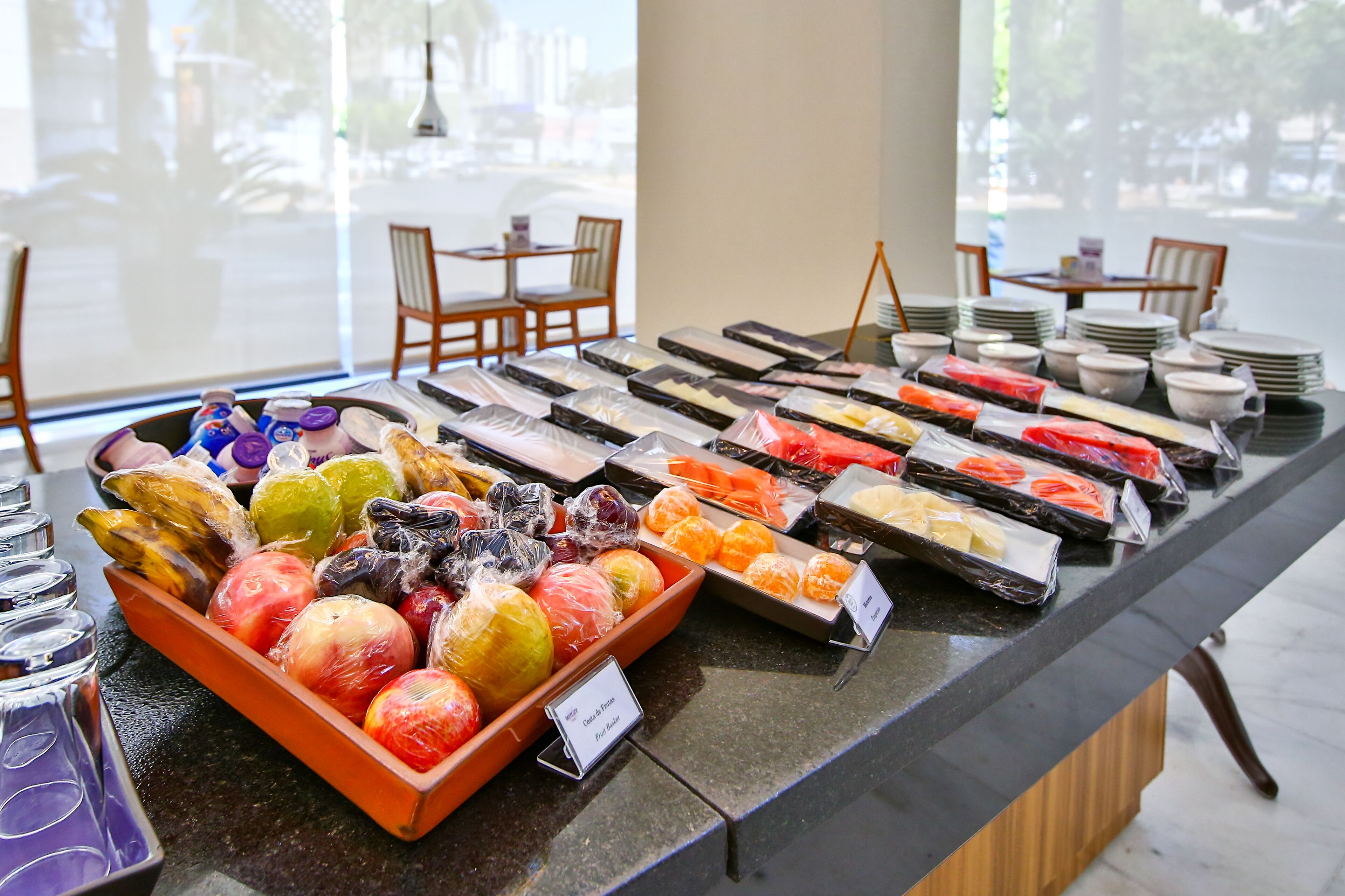 A buffet with various fruits and dishes, including a bowl of apples and a tray of oranges.