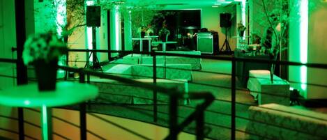 A lobby with a staircase, seating areas, and a stage with speakers.