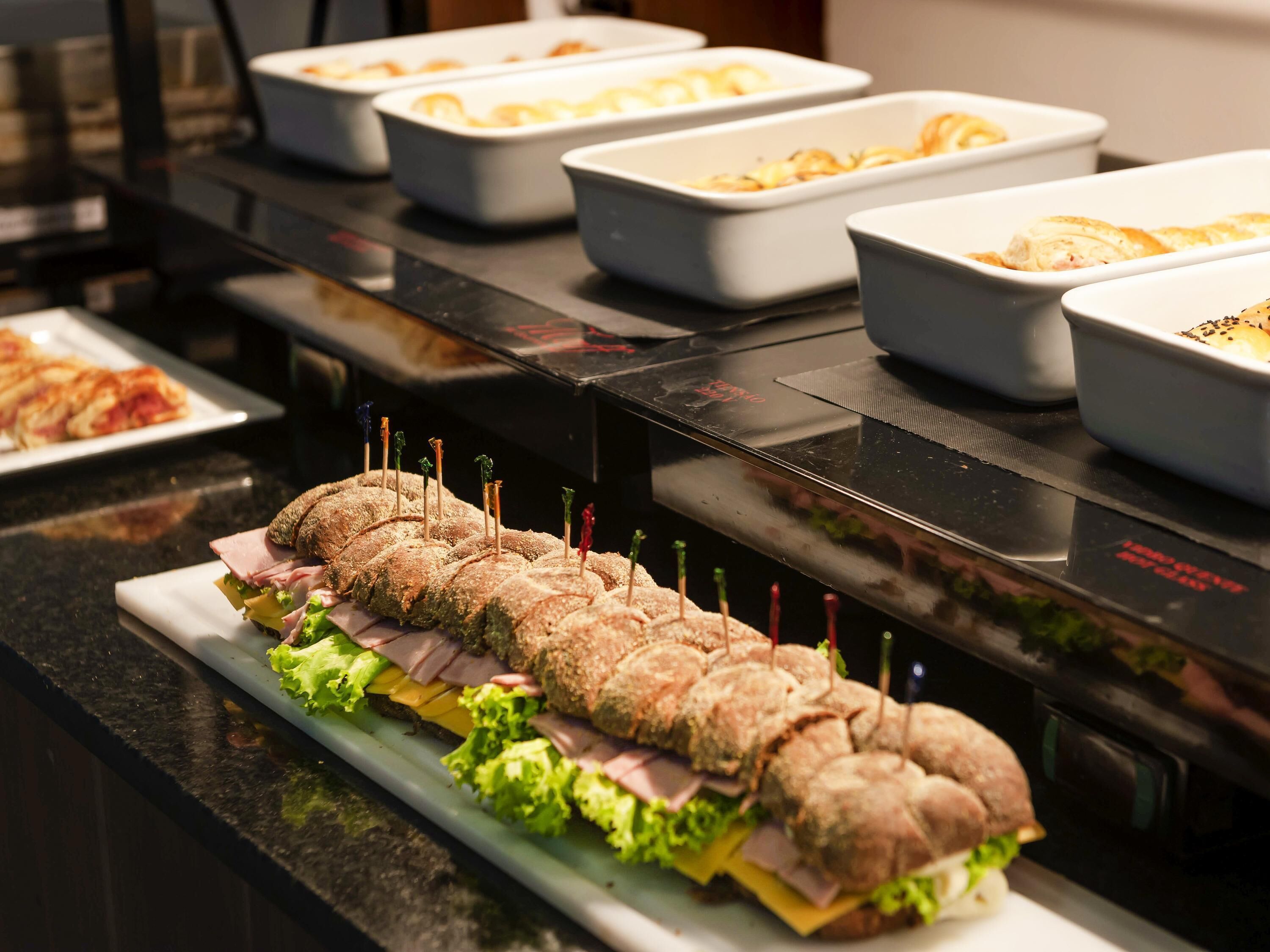 A buffet with a variety of dishes including sandwiches, salads, and other prepared foods.