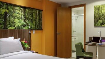 Une chambre d’hôtel avec un lit, un bureau avec un ordinateur portable, une douche et une grande fresque murale.