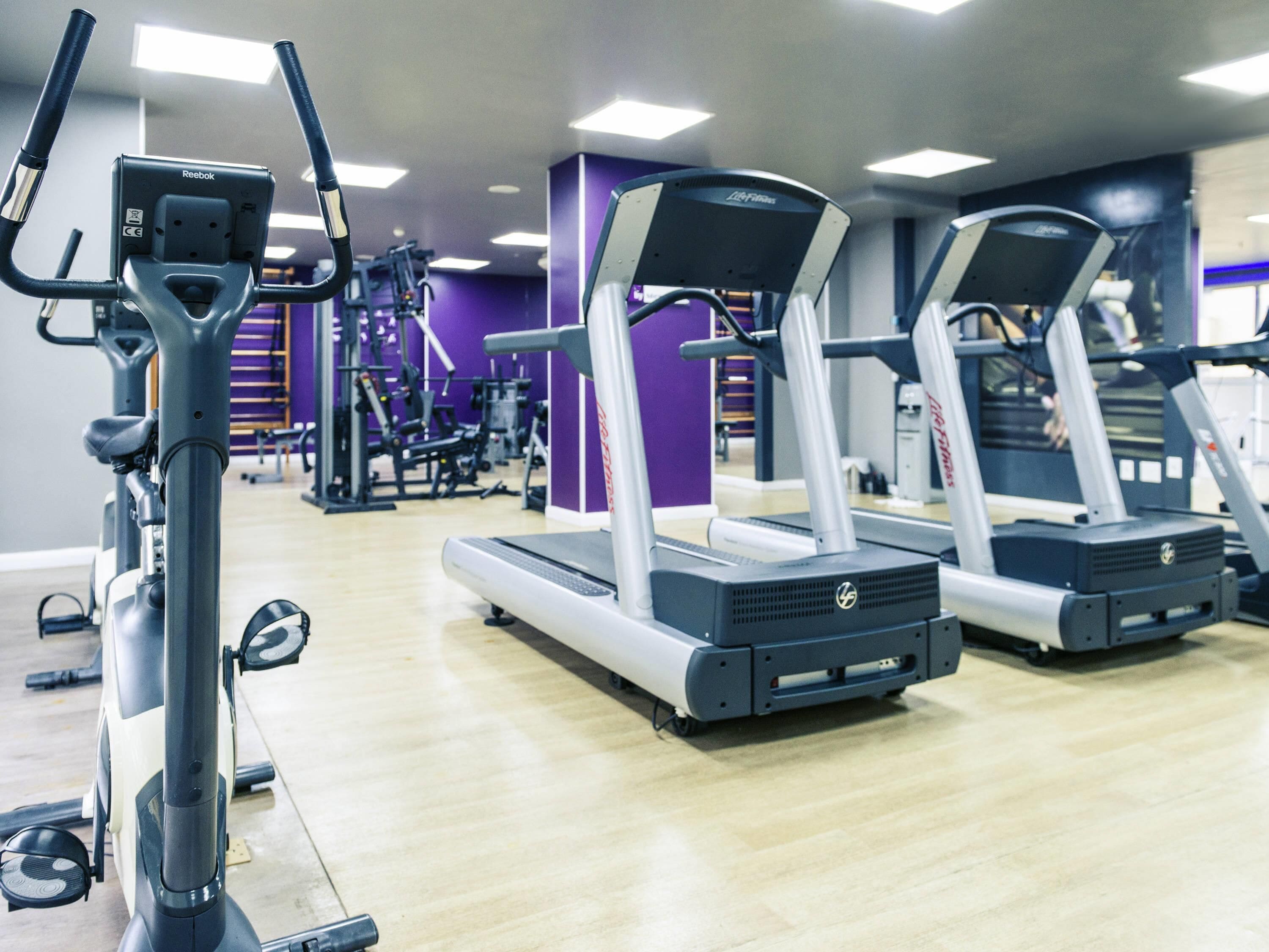 Une salle de sport équipée de tapis de course, de vélos d’exercice et d’appareils de musculation.