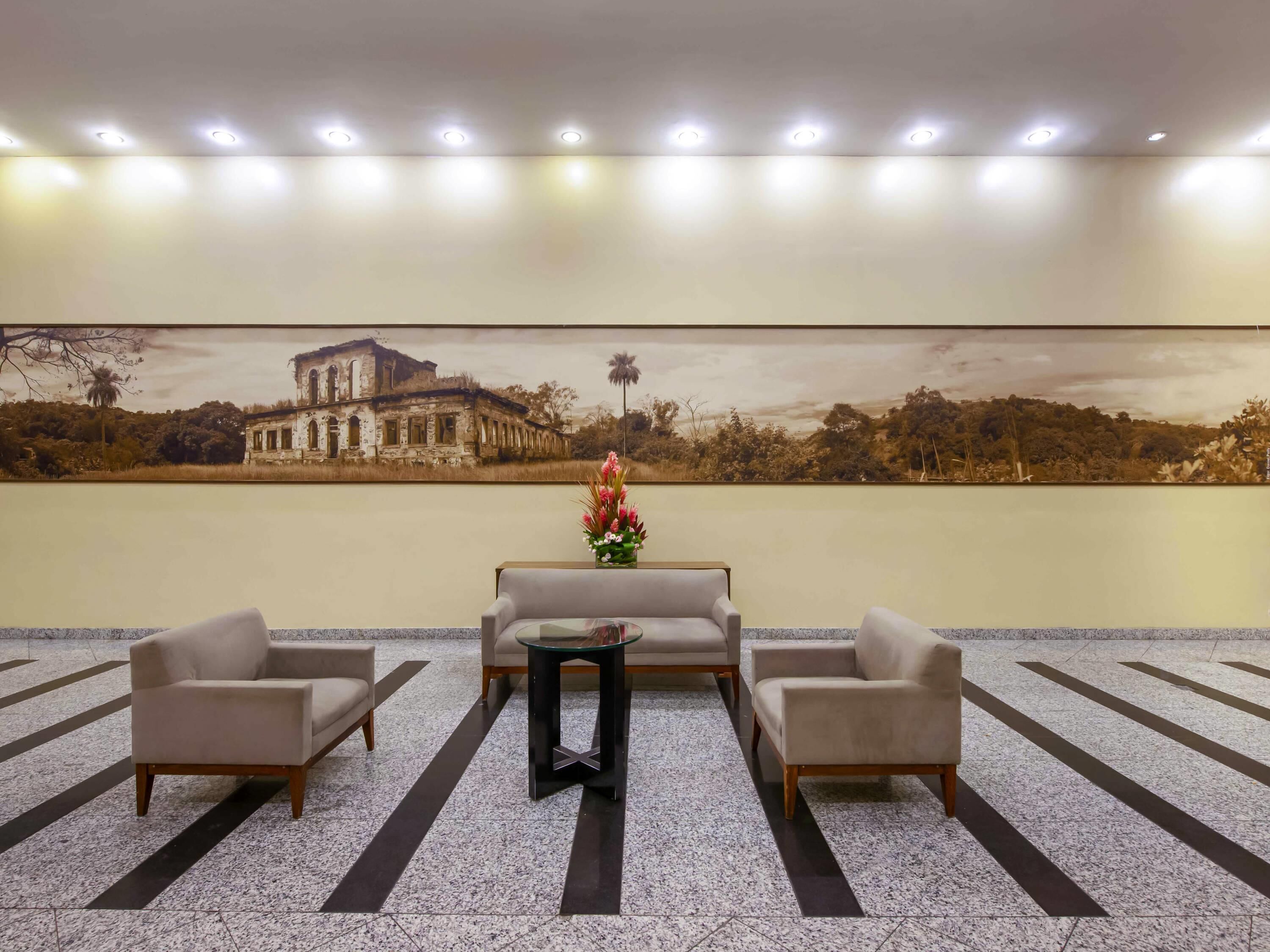A lobby with a seating area, a wall-mounted painting, and a tiled floor.
