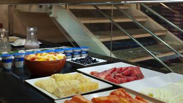 A buffet with various food items including fruits, meats, and dairy products.