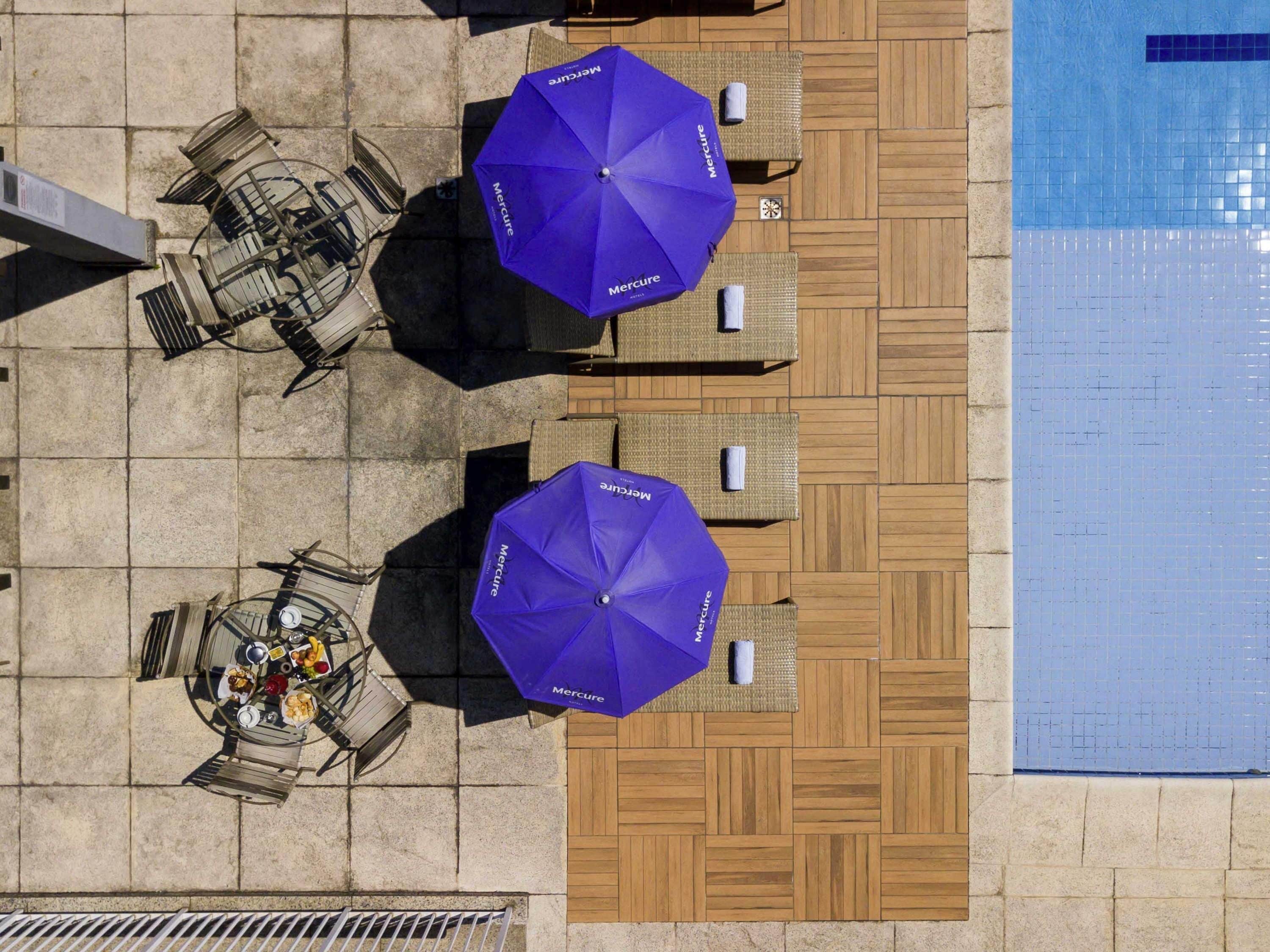 Een buitenzwembad, parasols bij het zwembad en ligstoelen