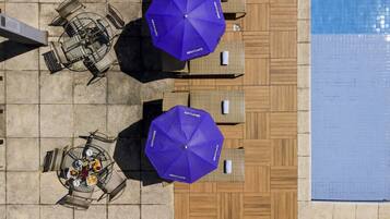 Een buitenzwembad, parasols bij het zwembad en ligstoelen