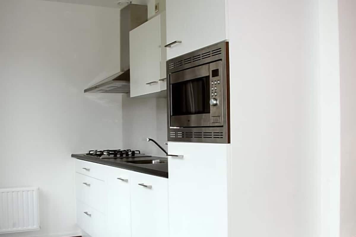 A kitchen with white cabinets, a built-in microwave, and a gas stove.