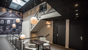 A modern interior with a staircase, seating area, and a view of a building through a glass wall. - Het Raedthuys Restaurant & Suites (Sint Maartensdijk)