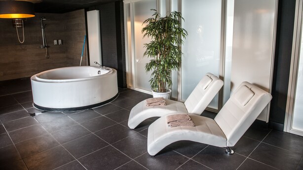 A modern spa room with a large bathtub, two reclining chairs, and a potted plant. - Het Raedthuys Restaurant & Suites (Sint Maartensdijk)