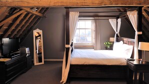 A bedroom with a bed, a TV, a dresser, and a window with curtains. - Het Raedthuys Restaurant & Suites (Sint Maartensdijk)