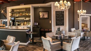 A bar area with a variety of liquor bottles, a chalkboard menu, and a mounted animal head. There are multiple seating areas with tables and chairs. - Het Raedthuys Restaurant & Suites (Sint Maartensdijk)