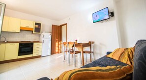 A compact living space with a kitchenette, a dining area, and a seating area with a sofa and chairs.