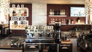 A bar and bistro area with a coffee machine, shelves of liquor bottles, and a menu board. - Resort Hotel Rocca di Vadaro (Ricadi)