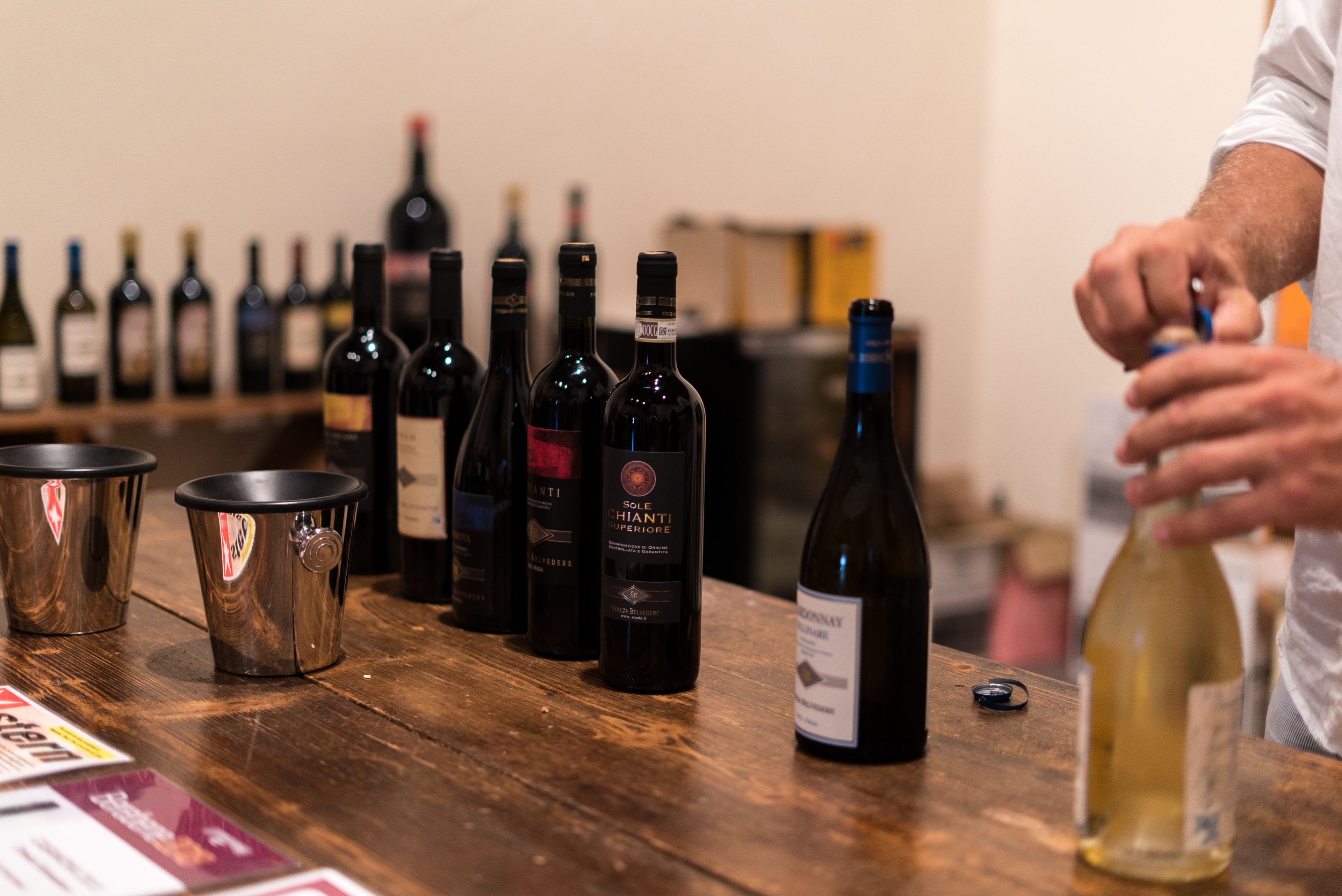 A wooden table with several wine bottles and metal cups.