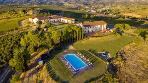 Vista aérea de una propiedad con varias edificaciones, piscina y viñedos circundantes.