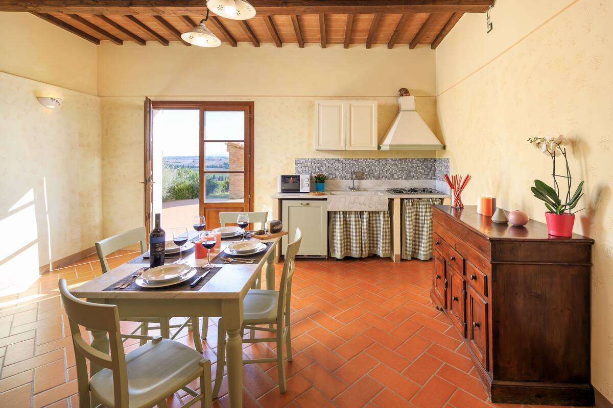 Una cocina con una mesa de comedor, sillas, estufa y armarios.