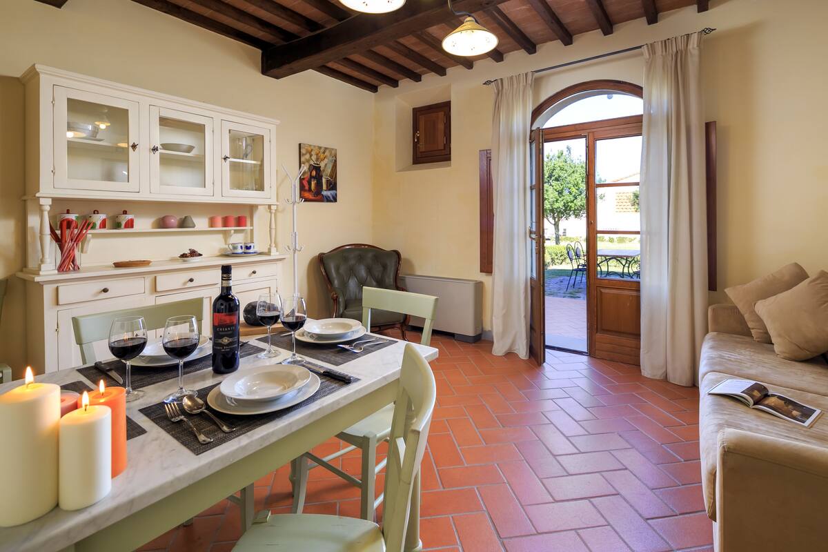 Un comedor con una mesa preparada para dos, un sofá y vistas al exterior.