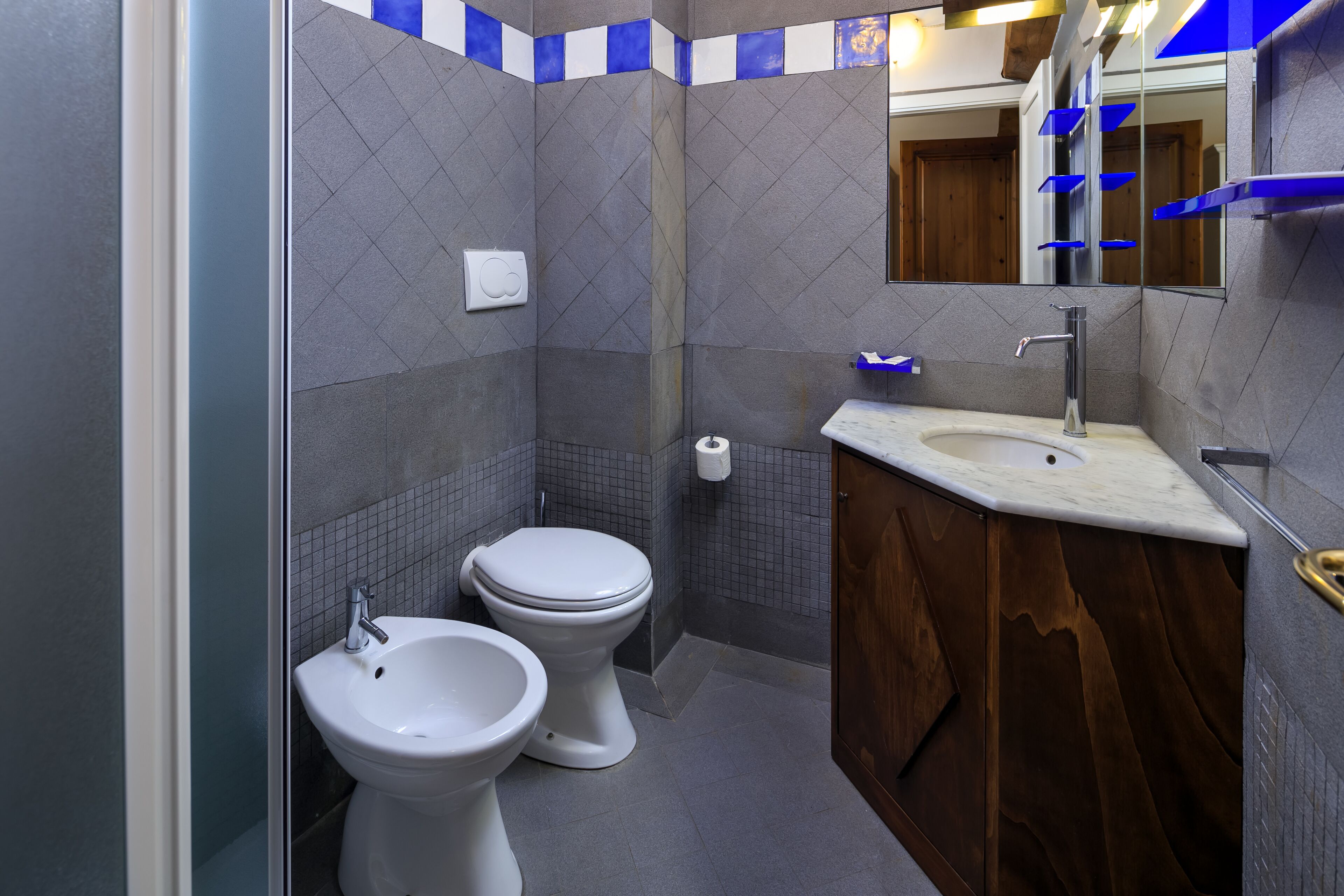 Ein Badezimmer mit zwei Toiletten, einem Waschbecken und einem Spiegel.