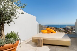 A modern balcony with a minimalist bed, a potted plant, and a view of the sea and buildings. - Higueron Hotel Malaga, Curio Collection by Hilton (Fuengirola)