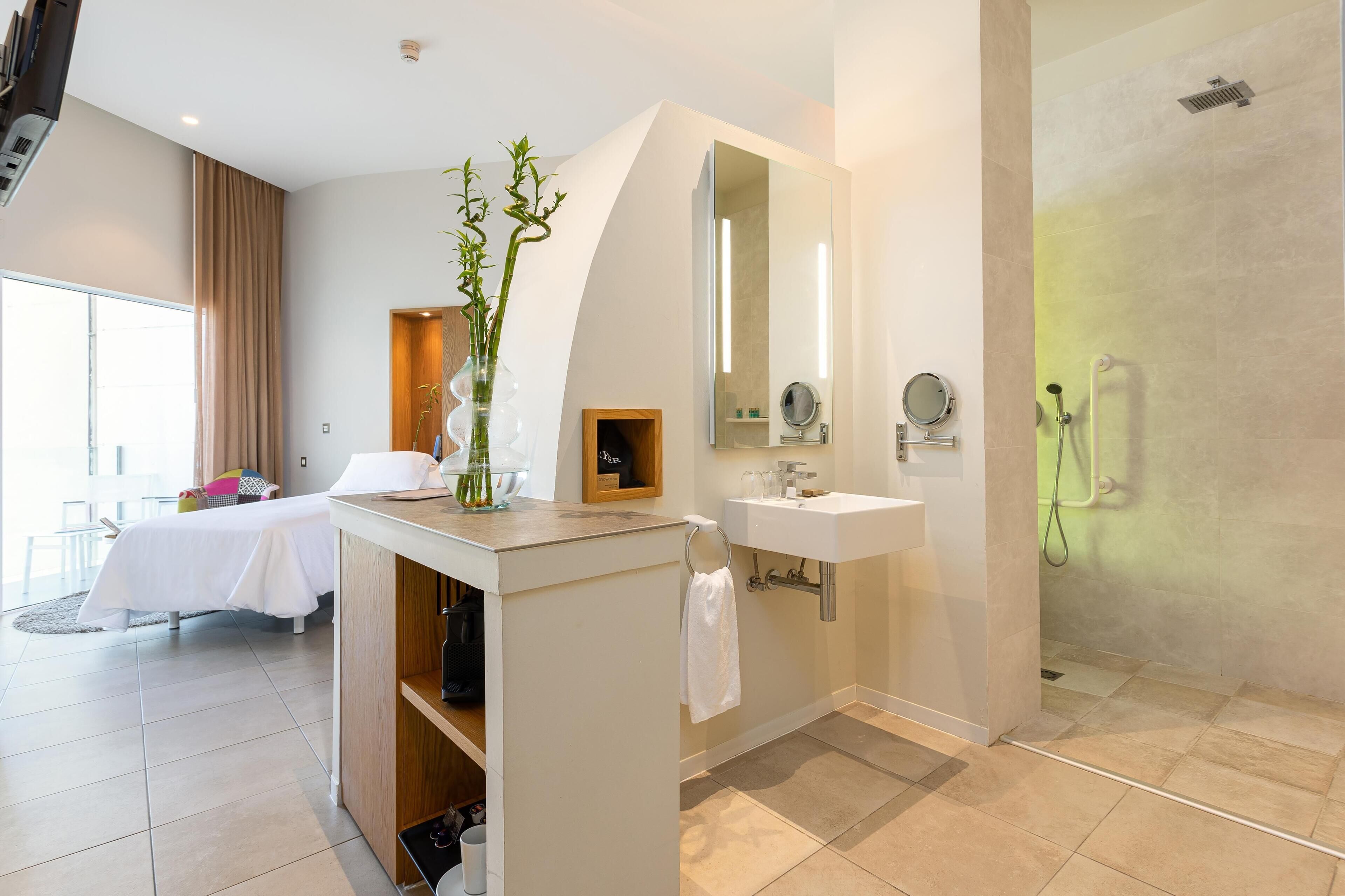 Une salle de bain moderne d’hôtel, équipée d’une douche, d’un lavabo et d’un meuble-lavabo.