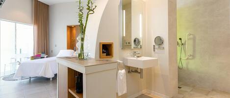 Une salle de bain moderne d’hôtel, équipée d’une douche, d’un lavabo et d’un meuble-lavabo.
