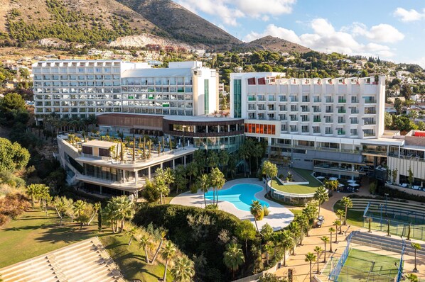A hotel with multiple buildings, a swimming pool, and palm trees. - Higueron Hotel Malaga, Curio Collection by Hilton (Fuengirola)