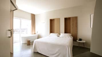 Une chambre d’hôtel moderne avec un grand lit, une petite table de chevet, une fenêtre avec des rideaux et une vue sur la ville.