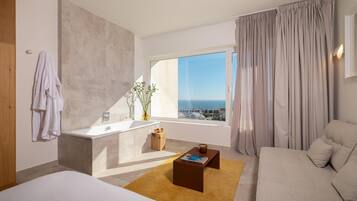 Una habitación de hotel moderna con un ventanal grande, una bañera, un sofá y una mesa de centro.