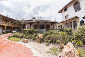 A courtyard with a patio, a stone wall, and a variety of plants and rocks.