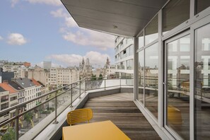Enjoy expansive city views from this balcony with a comfortable seating area and large windows.