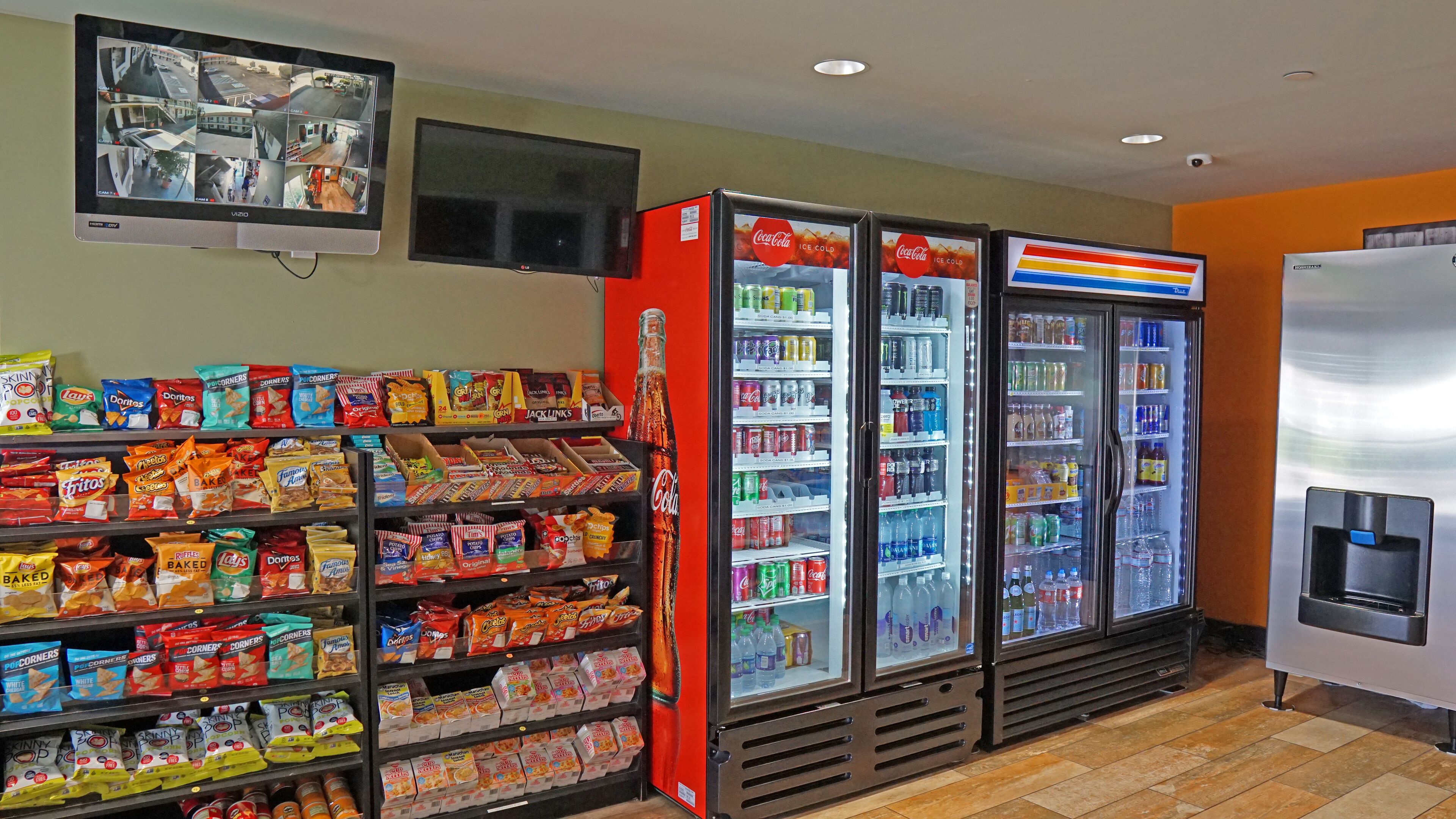 A snack and beverage area with shelves of chips, a Coca-Cola refrigerator, and a beverage cooler.